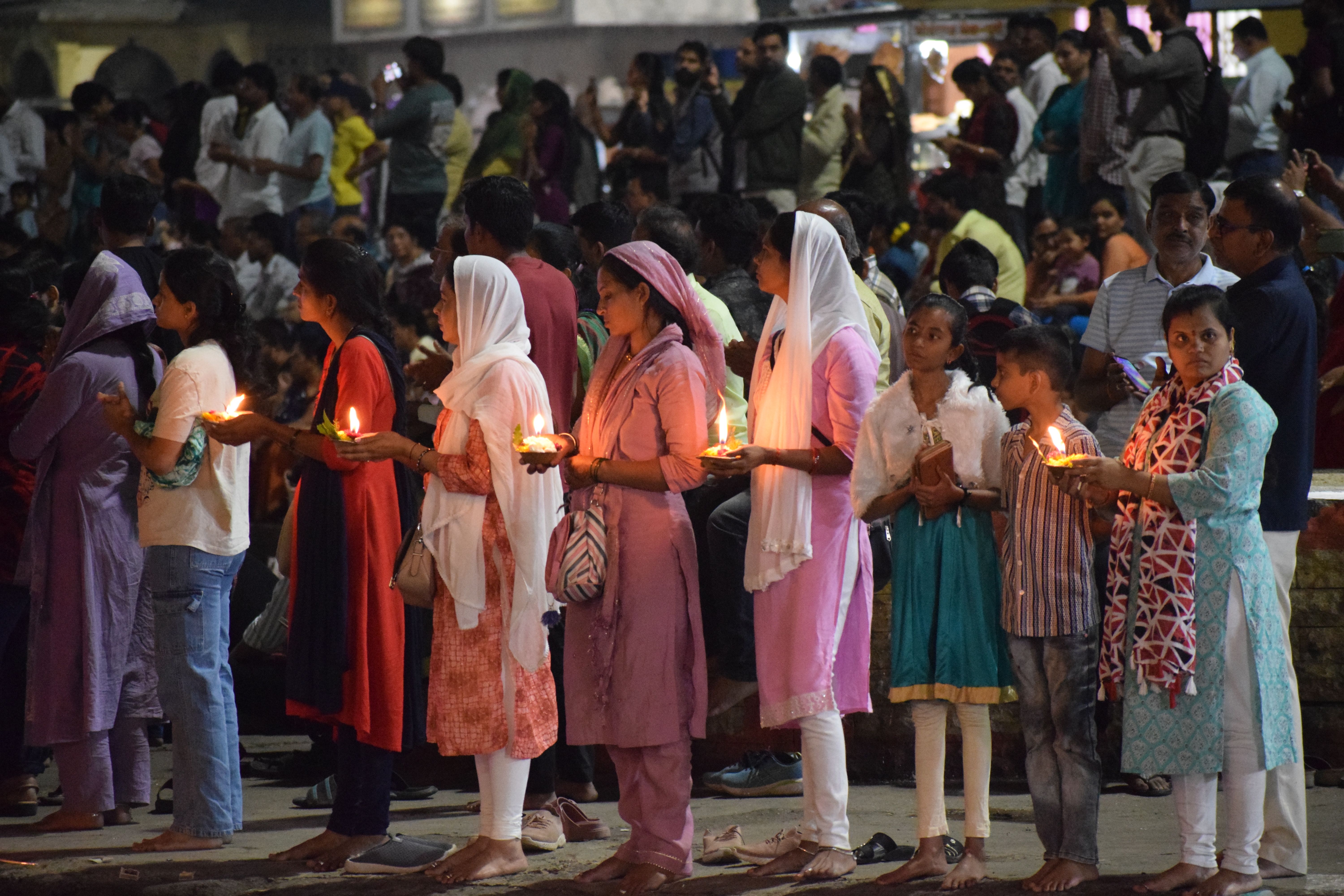 Devotees at Ganga aarti with their flowers and diya offerings, Ramkund, Panchavati, Nashik, Maharashtra. India