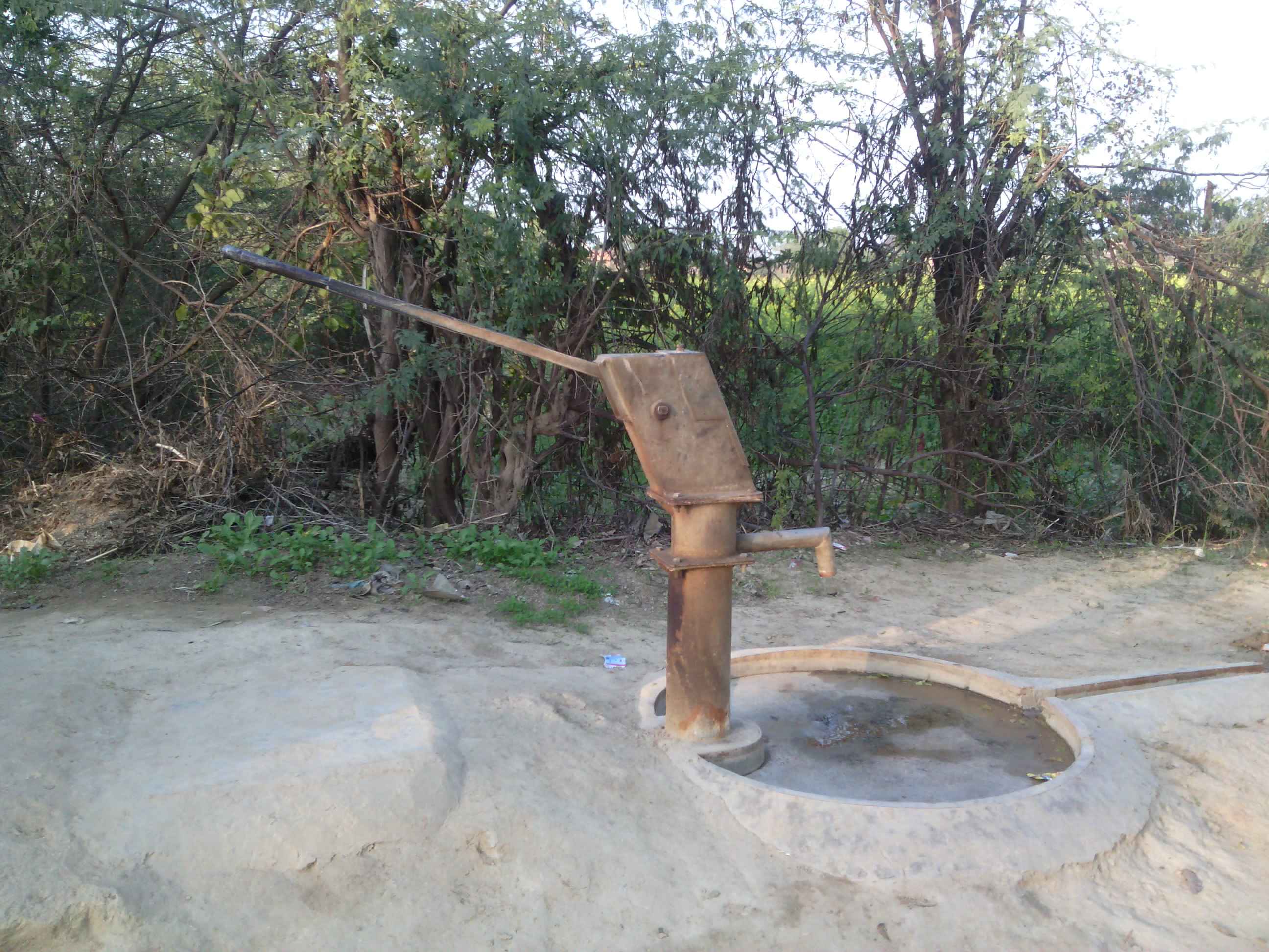 Drawing water through a handpump, interiors of Uttar Pradesh, India